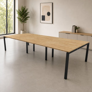 6 person bank of desks with oak-effect desk top and black frame in a clean, modern office interior