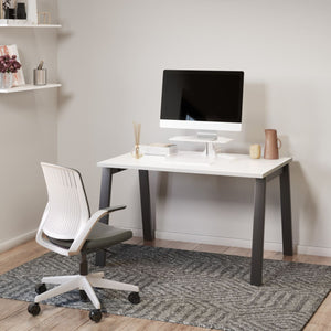 Electronic desk riser placed on a home office desk, creating a simple sit-stand workstation