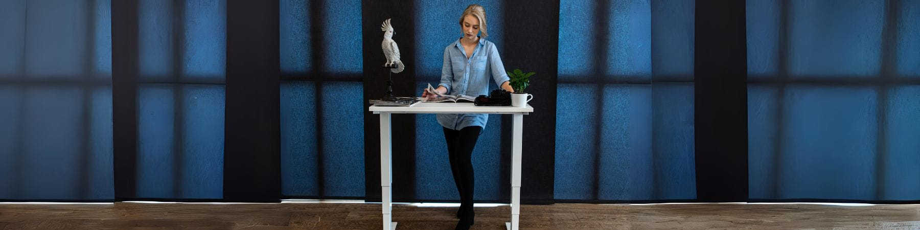 woman using a white small standing desk in a large room viewed from the front