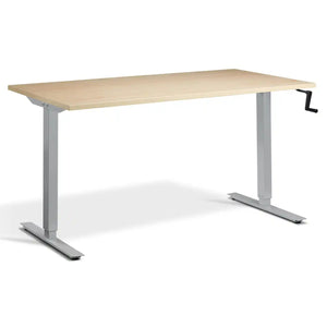 Hand crank sit stand desk with a maple desk top, silver frame and manual height adjustment handle