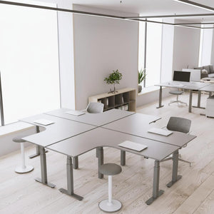 sit-stand corner desks in an office configured in a block of four
