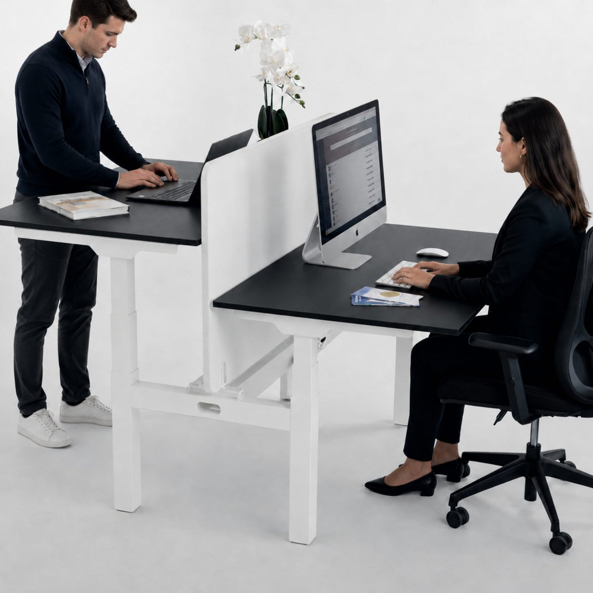 Two person standing desk with privacy screen and black desk tops in shared office setup