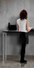 woman standing at a Rega standing desk in an office viewed from the rear