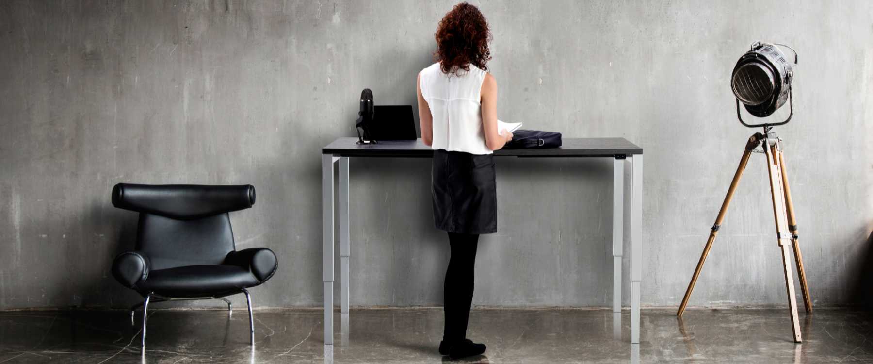 Height adjustable Ssanding desk in use in an office front view