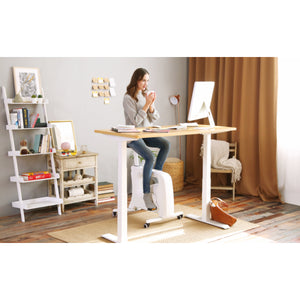 woman using under desk exercise bike at a standing desk viewed from the side